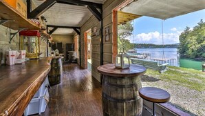 A rustic interior with a wooden bar, a round wooden table, and a view of a lake. - Live Love Lake | Blue Ridge, GA (Blue Ridge)