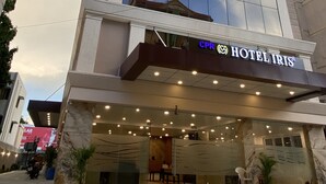 A modern hotel with a large glass facade, a visible emergency room sign, and a well-lit entrance area. - IRIS HOTEL TIRUPATI (Tirupati)