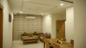 A modern living room with a dining area, wooden furniture, and a textured wall. - IRIS HOTEL TIRUPATI (Tirupati)
