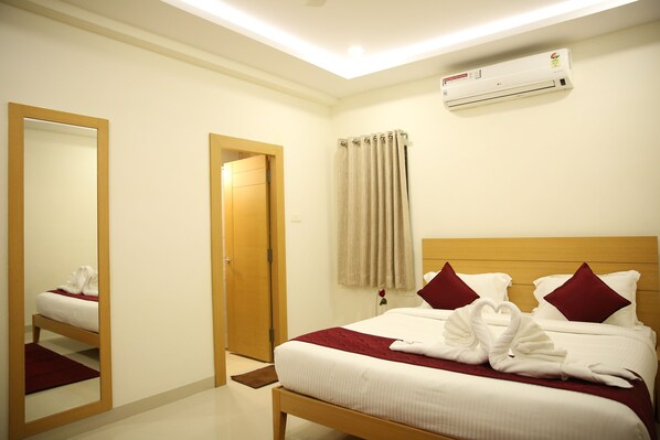 Habitación de hotel con cama, espejo, puerta y equipo de aire acondicionado.