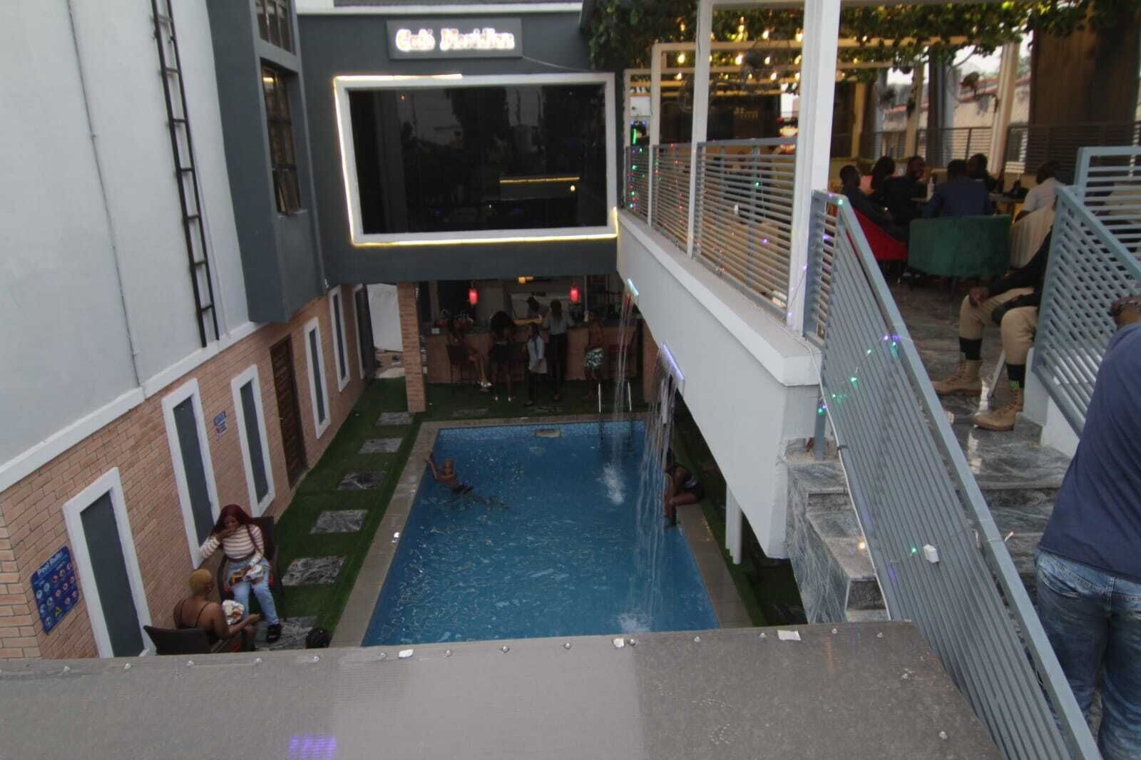 An indoor swimming pool with a view of a restaurant and a bar area.