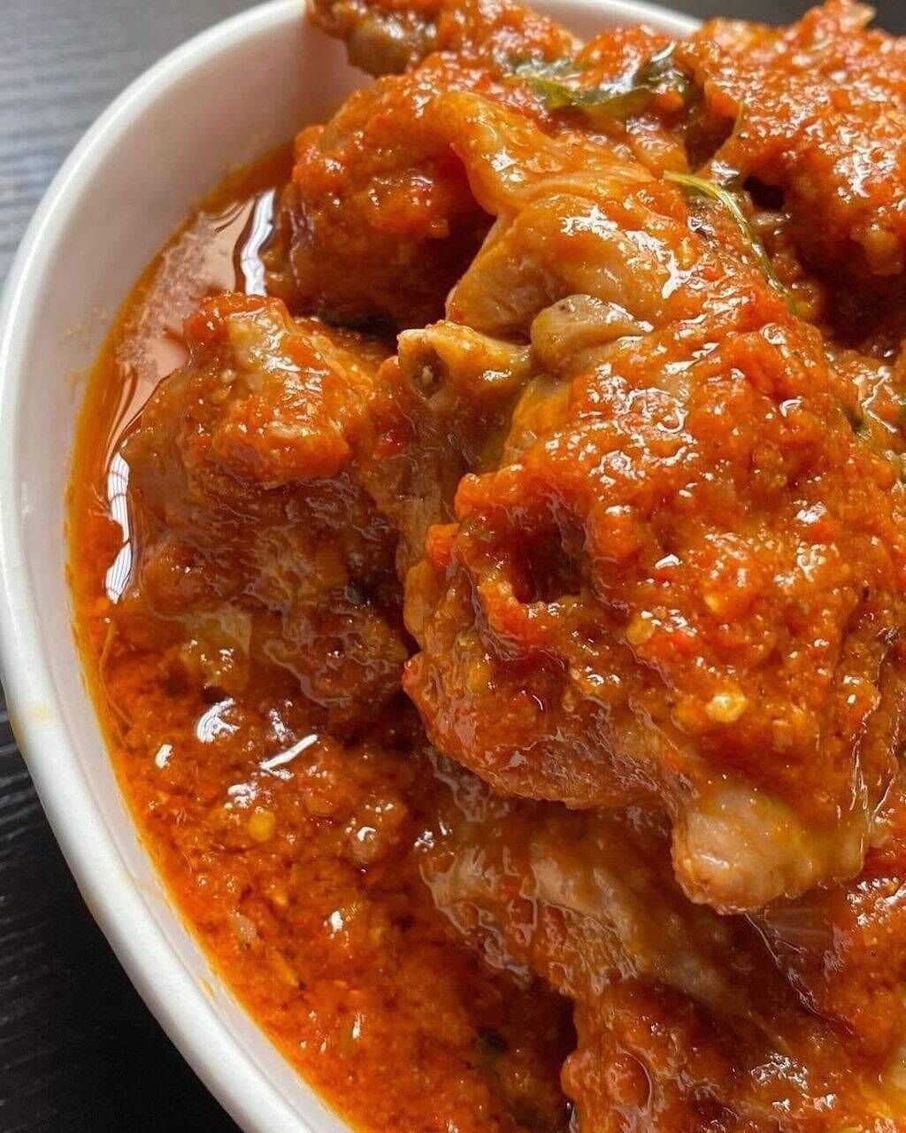 A bowl of chicken curry with visible spices and herbs.