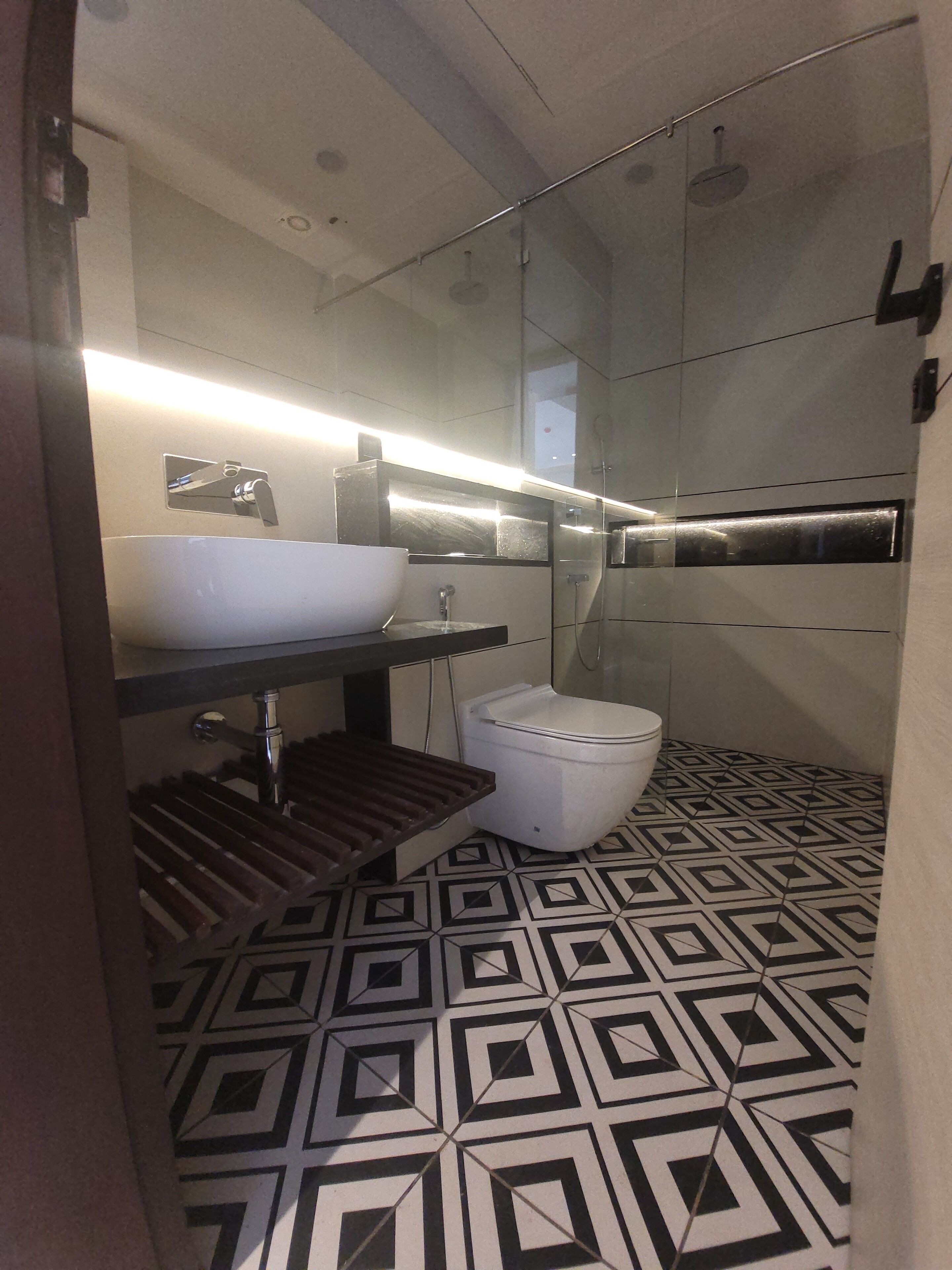 Un baño moderno con suelo de diseño geométrico, un lavabo blanco y zona de ducha.
