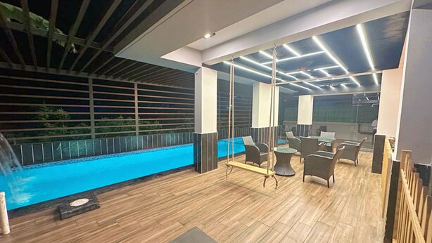 A modern lounge area with a pool, wooden flooring, and contemporary furniture. - Baga Bliss by Celestiial Hospitality (Calangute)