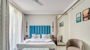 A modern hotel room with a large bed, a bedside table, a chair, and a mirror. - Baga Bliss by Celestiial Hospitality (Calangute)