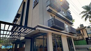 A modern hotel with a glass facade, multiple balconies, and a covered entrance area. - Baga Bliss by Celestiial Hospitality (Calangute)