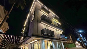 A modern hotel with a two-story structure, large glass windows, and a covered outdoor area with a pool. - Baga Bliss by Celestiial Hospitality (Calangute)