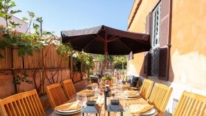 A round wooden table set for dining with chairs, a table umbrella, and lanterns. - Vacation home Randi by Interhome (Anzio)