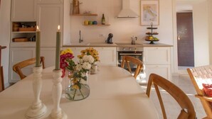 A kitchen with white cabinets, a stove, and a dining table with chairs. - Vacation home Randi by Interhome (Anzio)