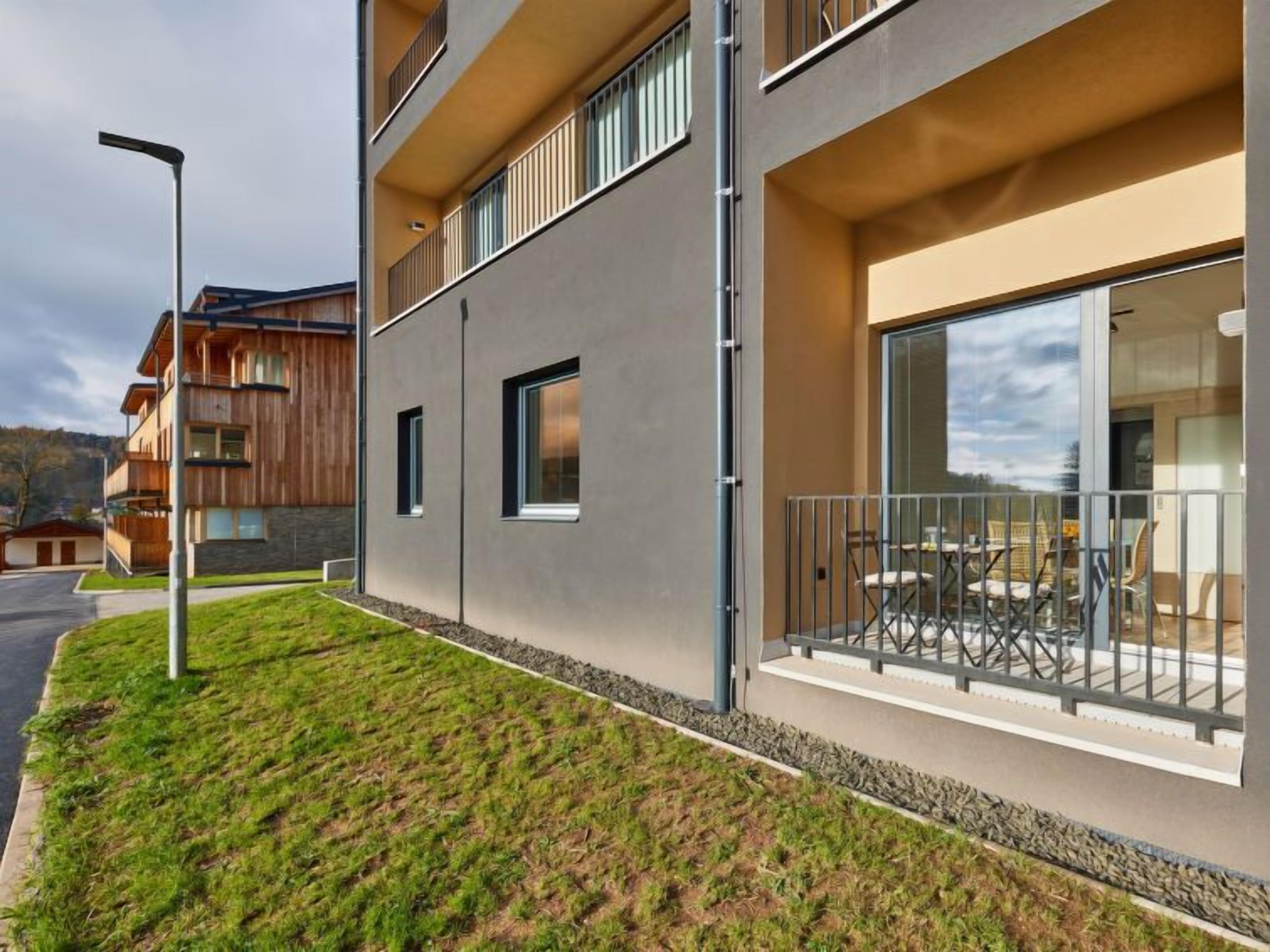 A modern multi-story building with a balcony area featuring outdoor seating.