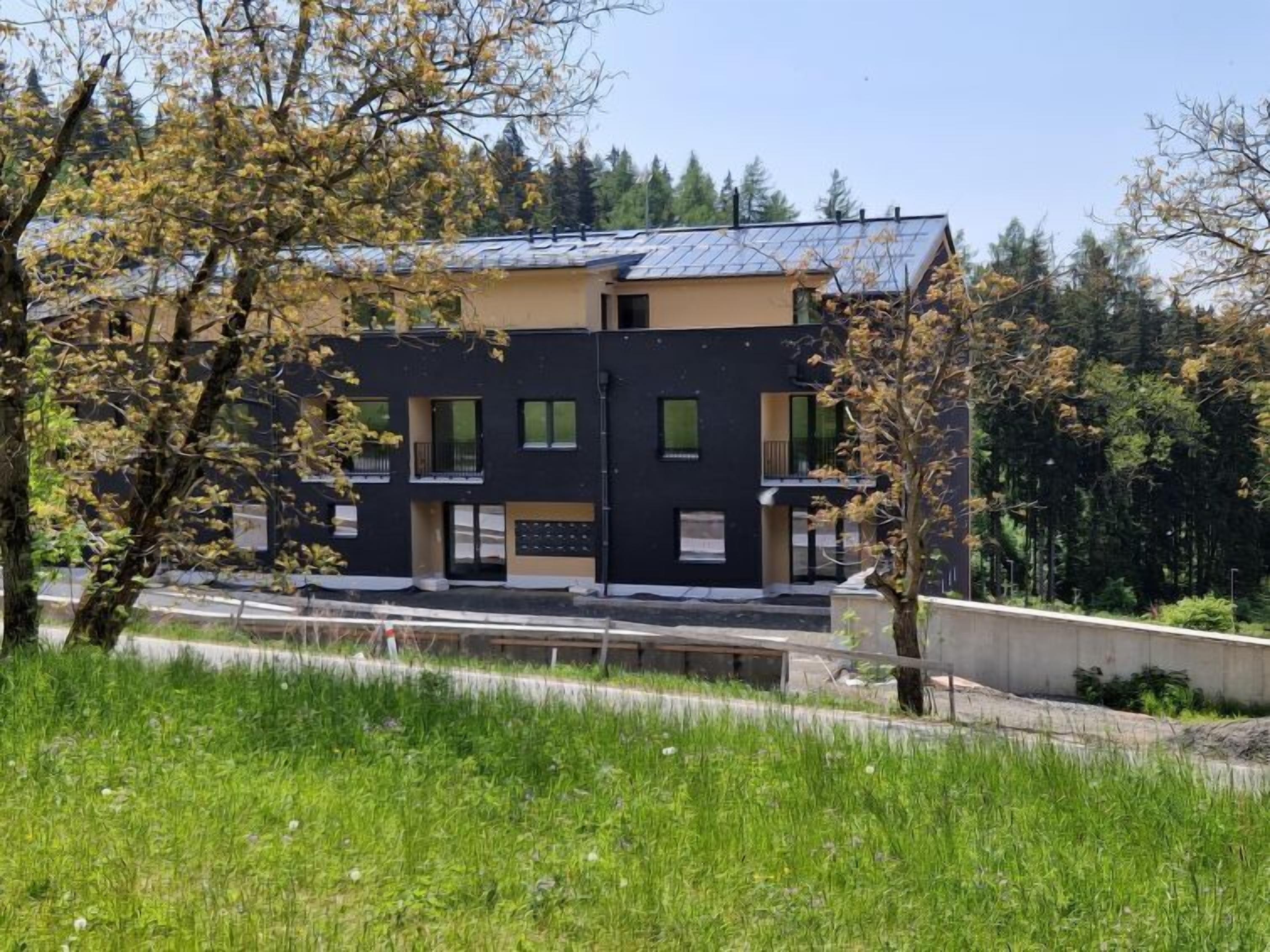 Een modern gebouw met een plat dak, veel ramen en een kleine ingang.