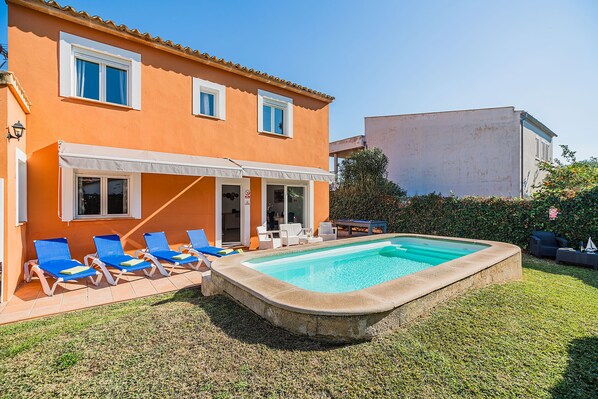 A two-story building with a swimming pool, outdoor seating, and a covered patio.