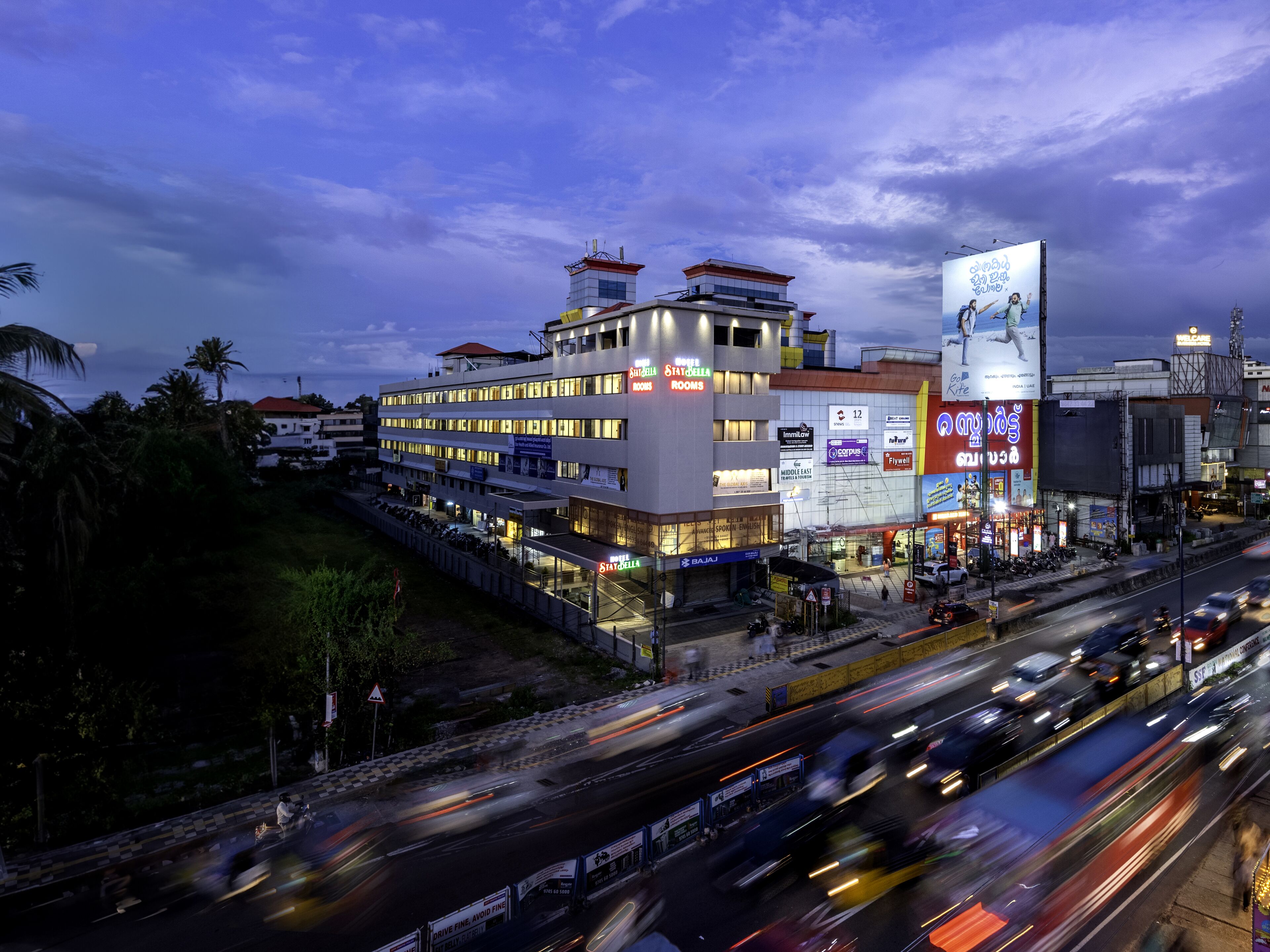 A multi-story hotel with a modern design, featuring multiple balconies and a prominent sign for 'State of Art Rooms'.