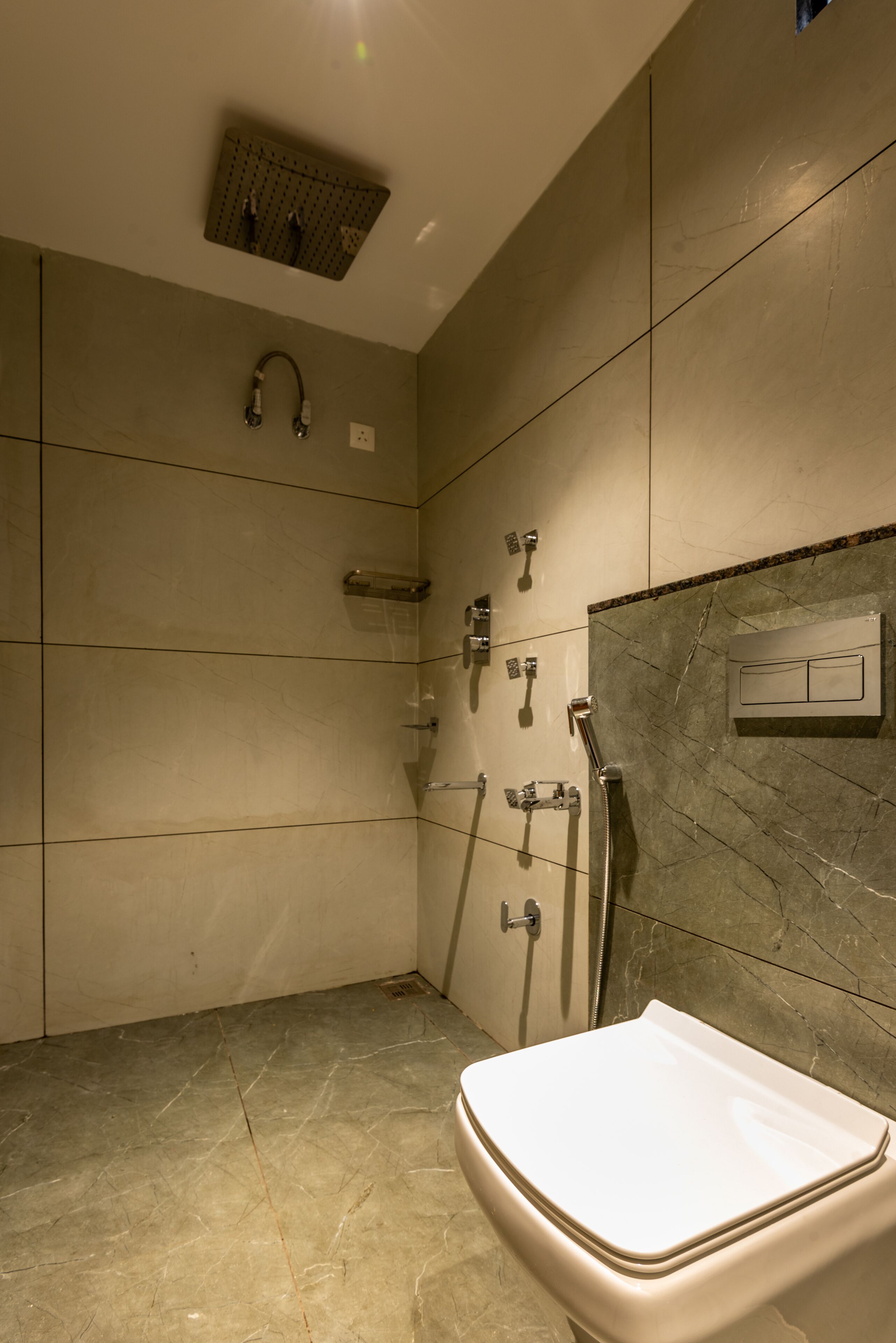 A modern bathroom with a shower, toilet, and a wall-mounted control panel.