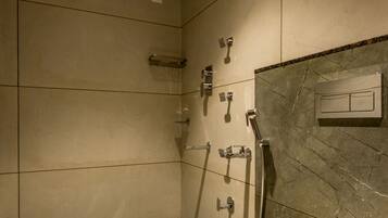 A modern bathroom with a shower, toilet, and a wall-mounted control panel.