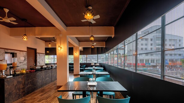 Un restaurante moderno con una barra alargada, sillas color turquesa y un amplio ventanal con vistas a la calle.