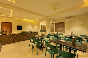 A modern dining area with marble counters, green chairs, and tables. - Hotel Stay Bella (Kozhikode)