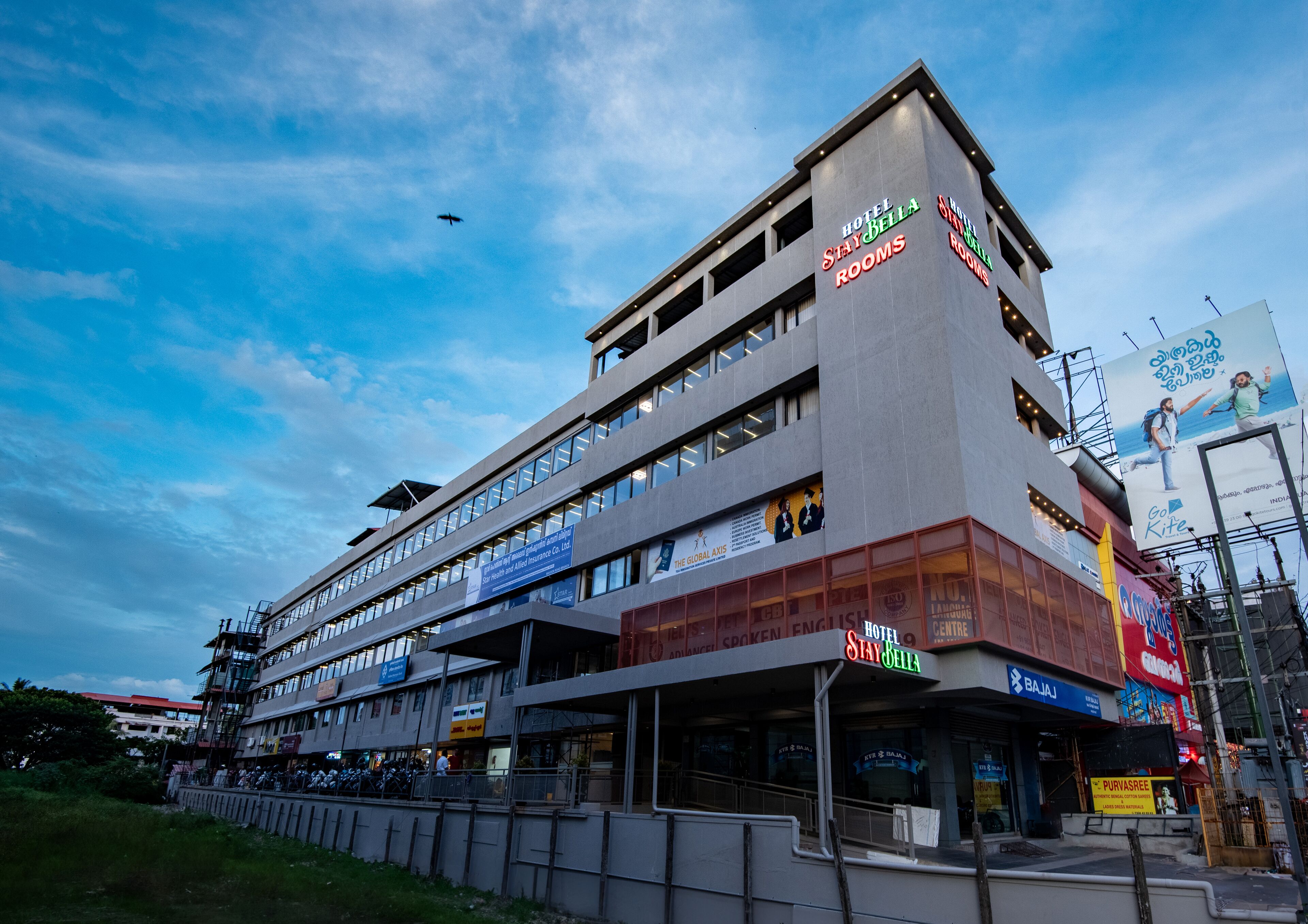 A multi-story hotel with signage for 'Hotel StayBella Rooms' and 'Hotel StayBella'.