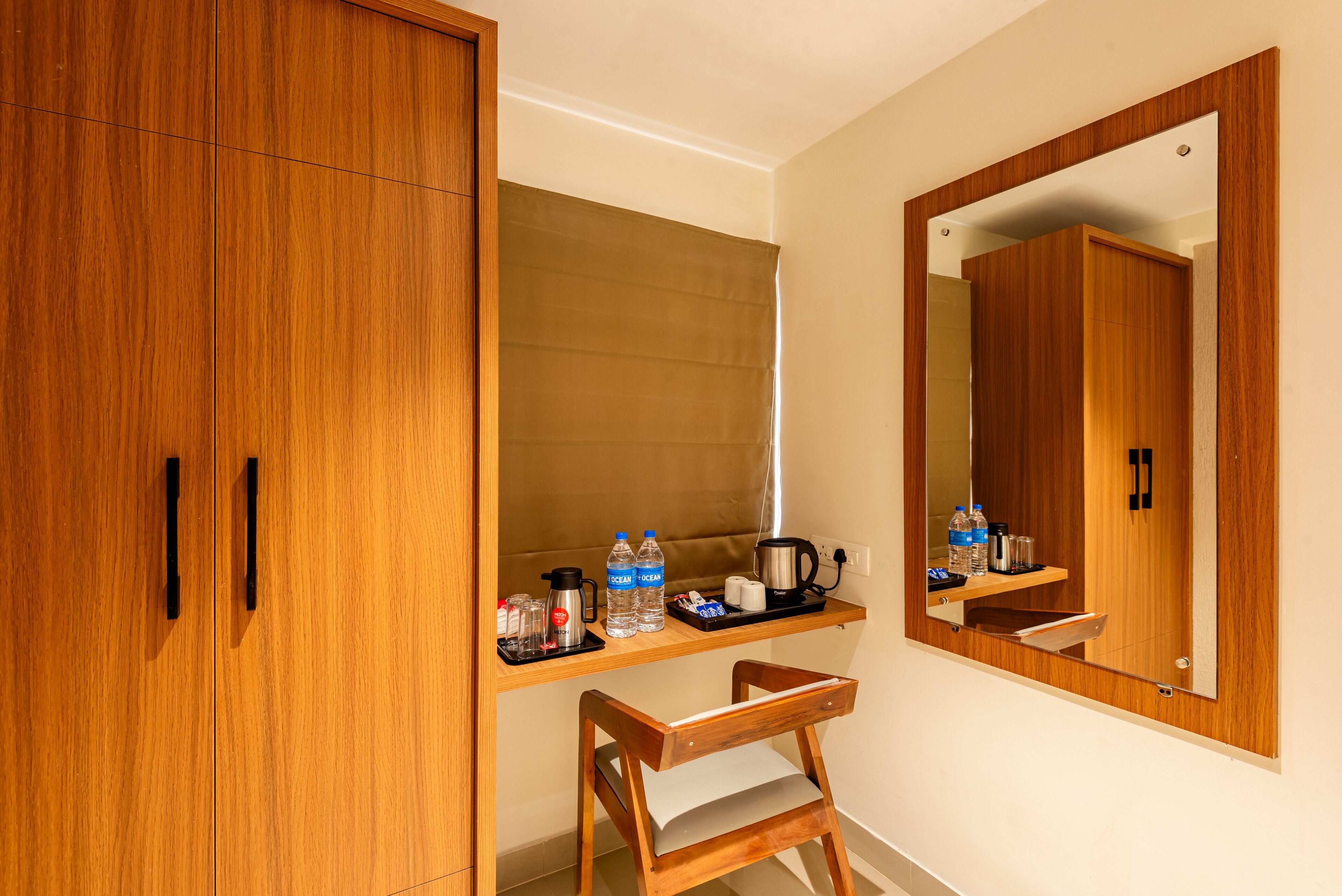 A wooden wardrobe with a mirror, a small wooden chair, and a shelf with toiletries.
