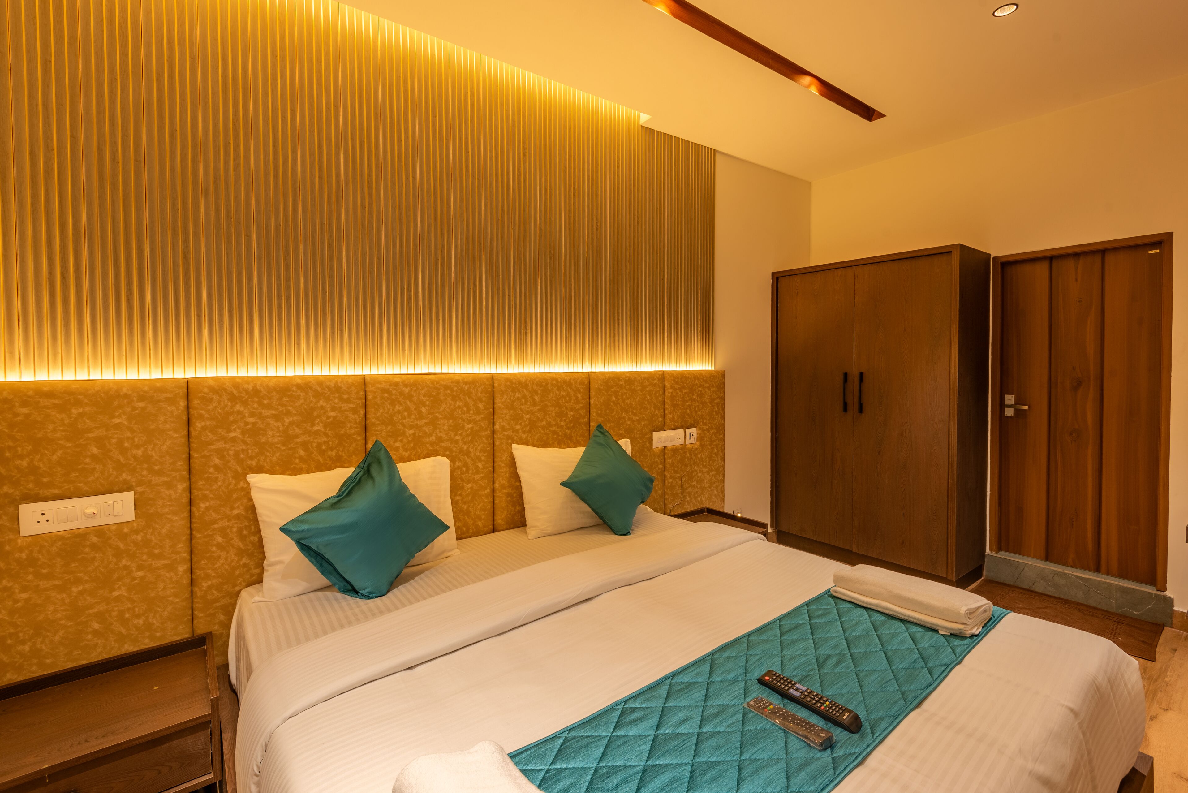 A hotel room with a bed, a wardrobe, and a wall with vertical lines.