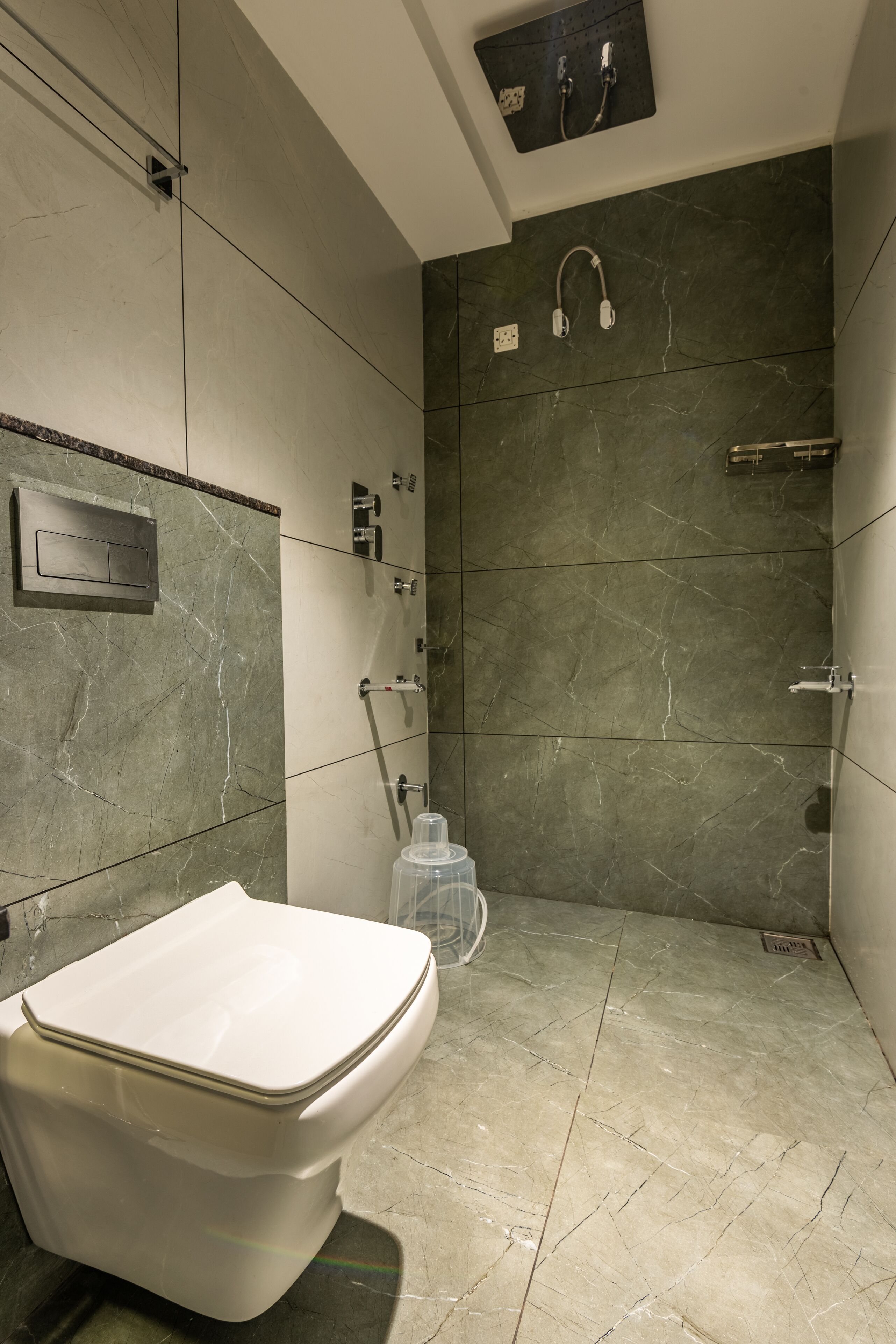 Un baño moderno con inodoro, ducha y paredes de mármol.