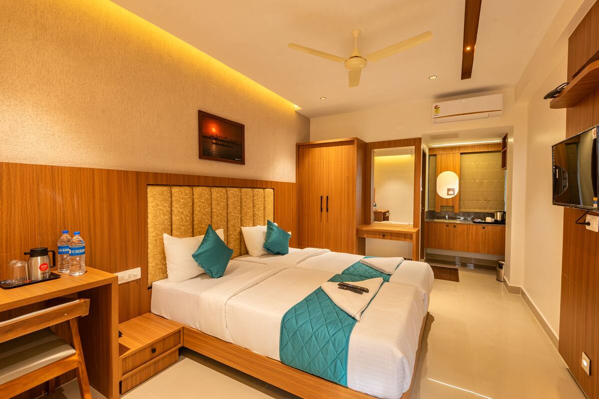 A hotel room with a bed, desk, and kitchenette.