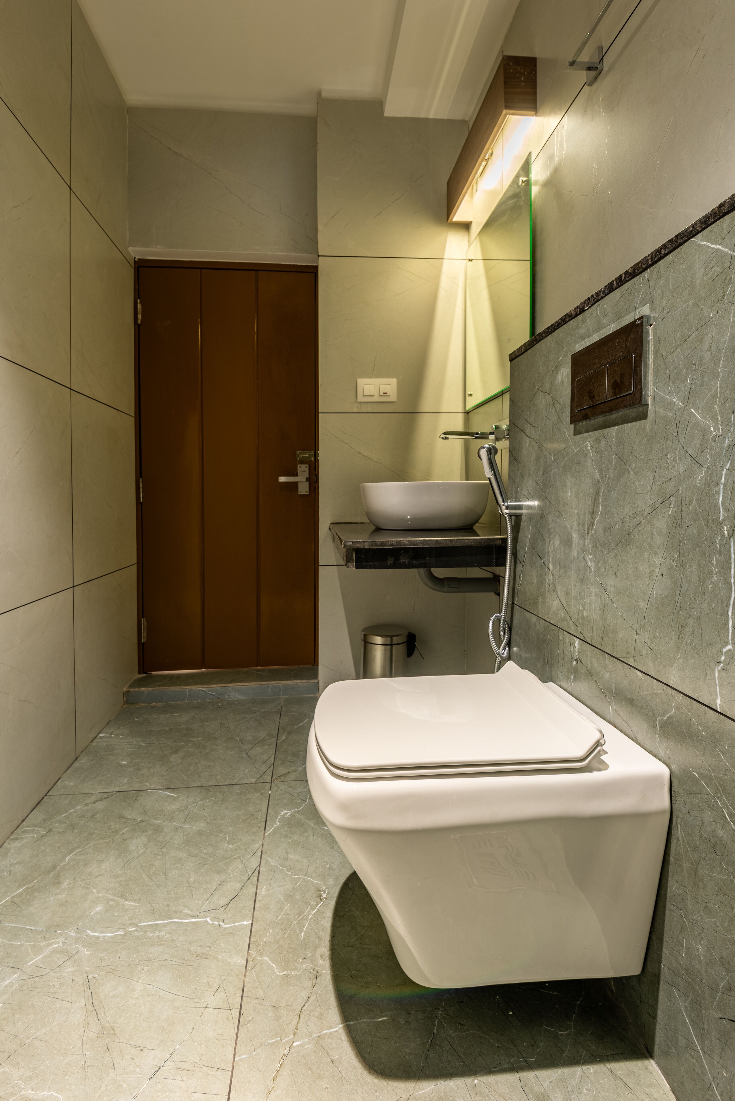 A modern bathroom with a white toilet, a sink with a vessel basin, and a shower.