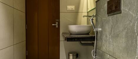 A modern bathroom with a white toilet, a sink with a vessel basin, and a shower.