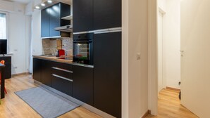 A modern kitchen with dark cabinetry, a built-in oven, and a countertop with a kettle. - Contarini by Interhome (Milan)