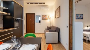 A modern kitchen with built-in appliances, a dining area with a table set for four, and a living area with a sofa and a painting. - Contarini by Interhome (Milan)