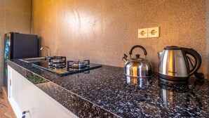 A kitchen with a granite countertop, a kettle, a coffee maker, and a stove.