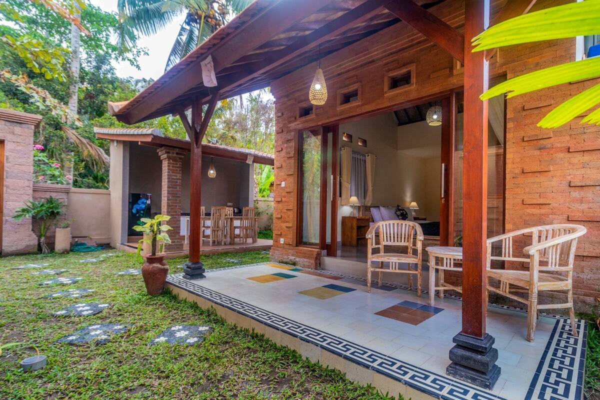 A covered outdoor seating area with wooden furniture and a tiled floor.