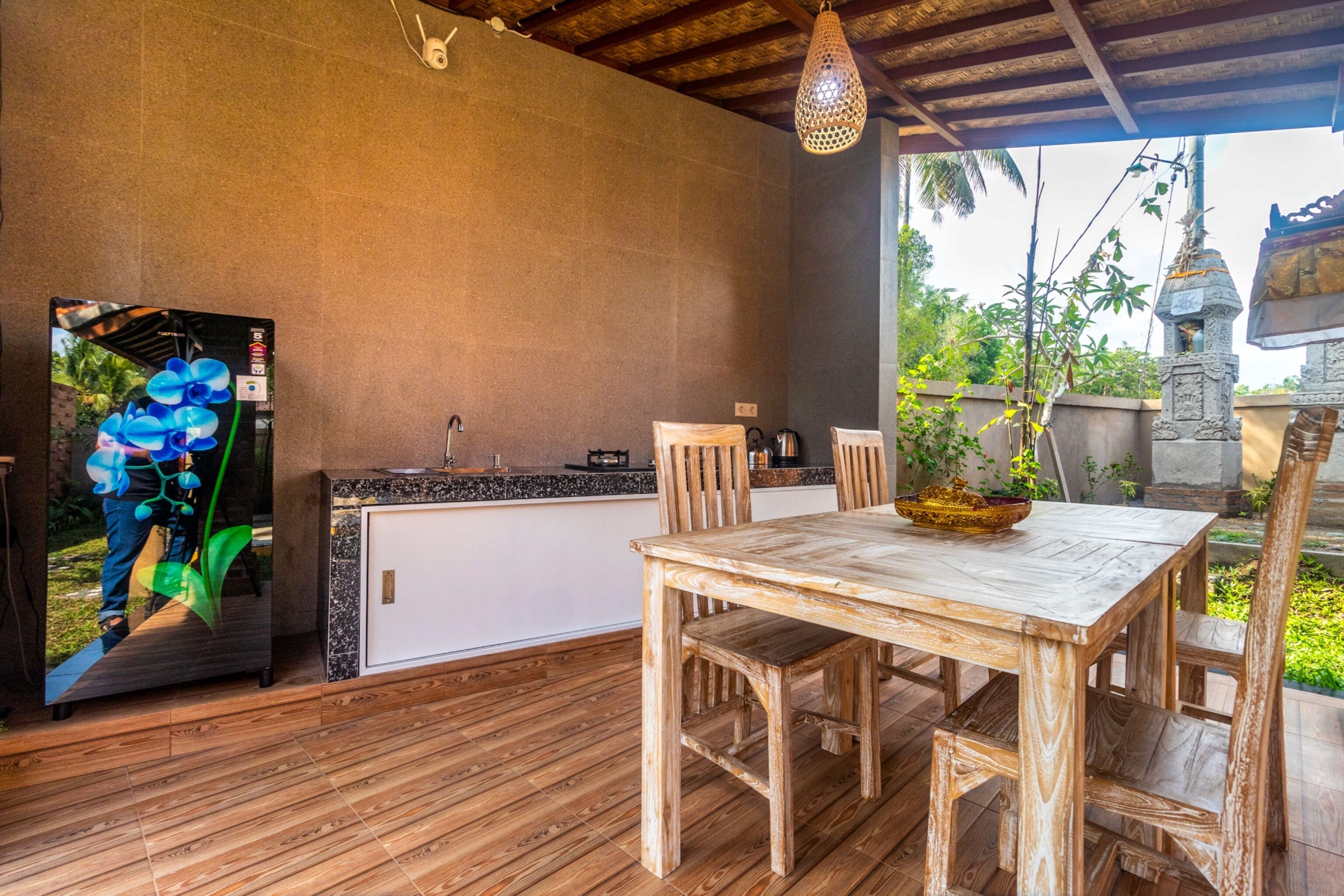 A wooden dining table with chairs, a kitchen area with a sink and counter, and a hanging light fixture.
