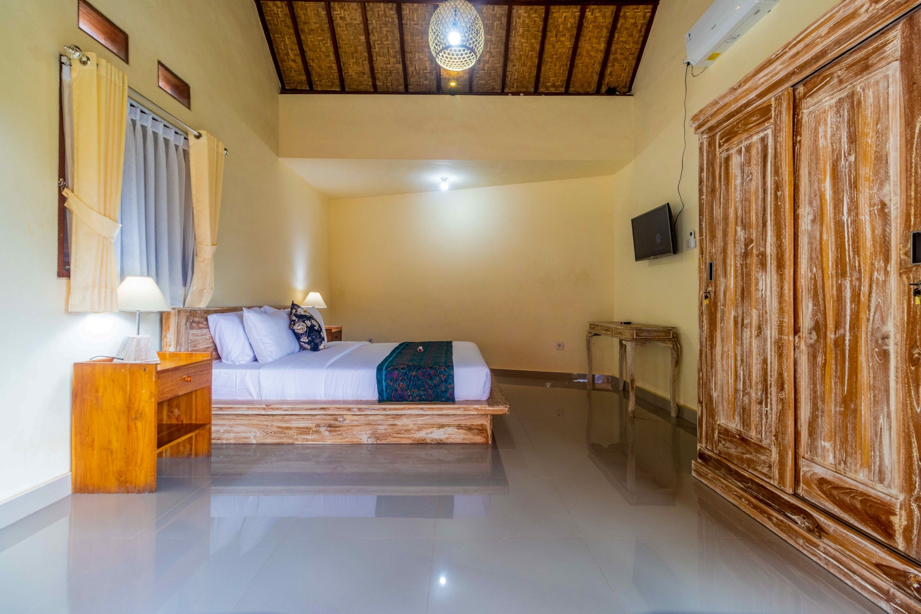 Une chambre à coucher avec un lit en bois, une table de chevet, une lampe, une armoire et un luminaire au plafond.