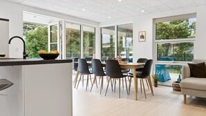 Une cuisine moderne avec un coin repas, de grandes fenêtres et une vue sur l’extérieur.