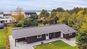 Une maison moderne avec un toit en tuiles, un patio couvert et une vue sur un lac.