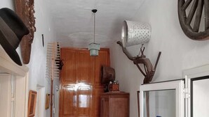 A hallway with wooden cabinets, a patterned floor, a ceiling fan, and a refrigerator.