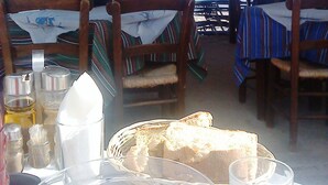 An outdoor dining area with tables and chairs, overlooking the sea.