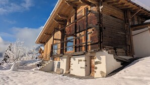 Eine Holzhütte mit geneigtem Dach, großen Fenstern und einem Steinfundament.