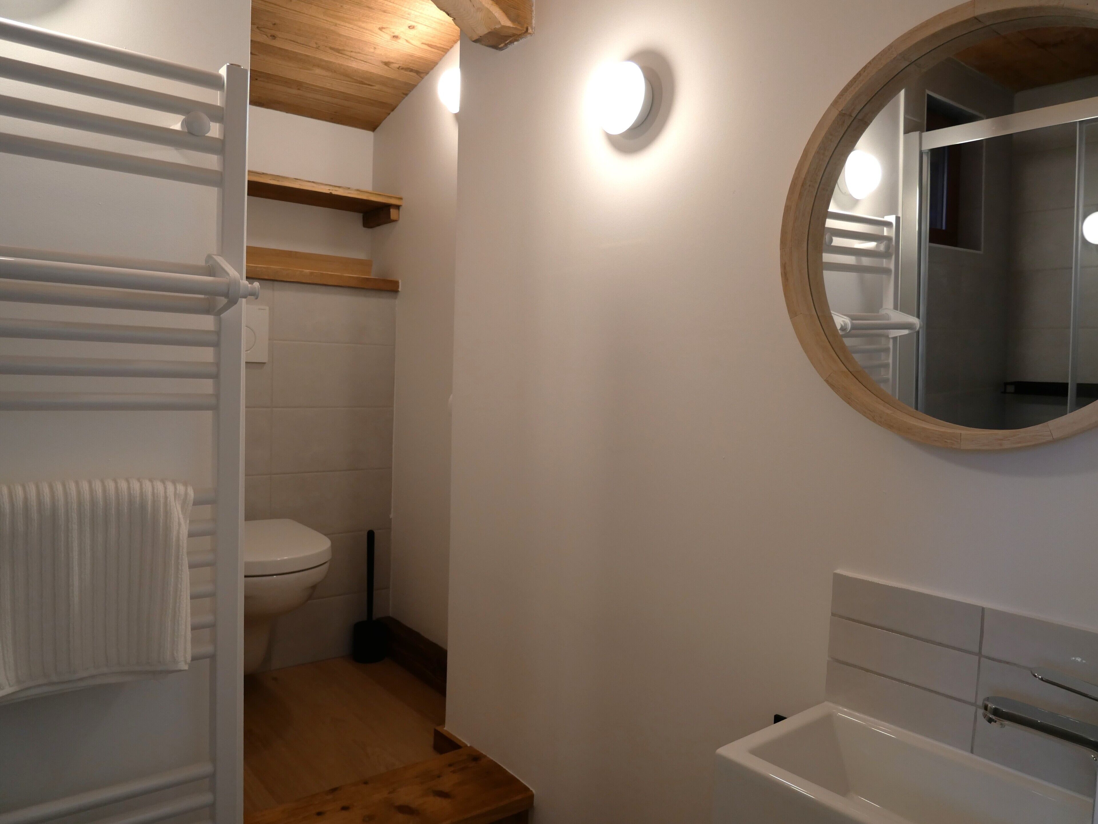 Ein Badezimmer mit Toilette, einer Holzablage, einem Handtuchhalter und einer Badewanne.