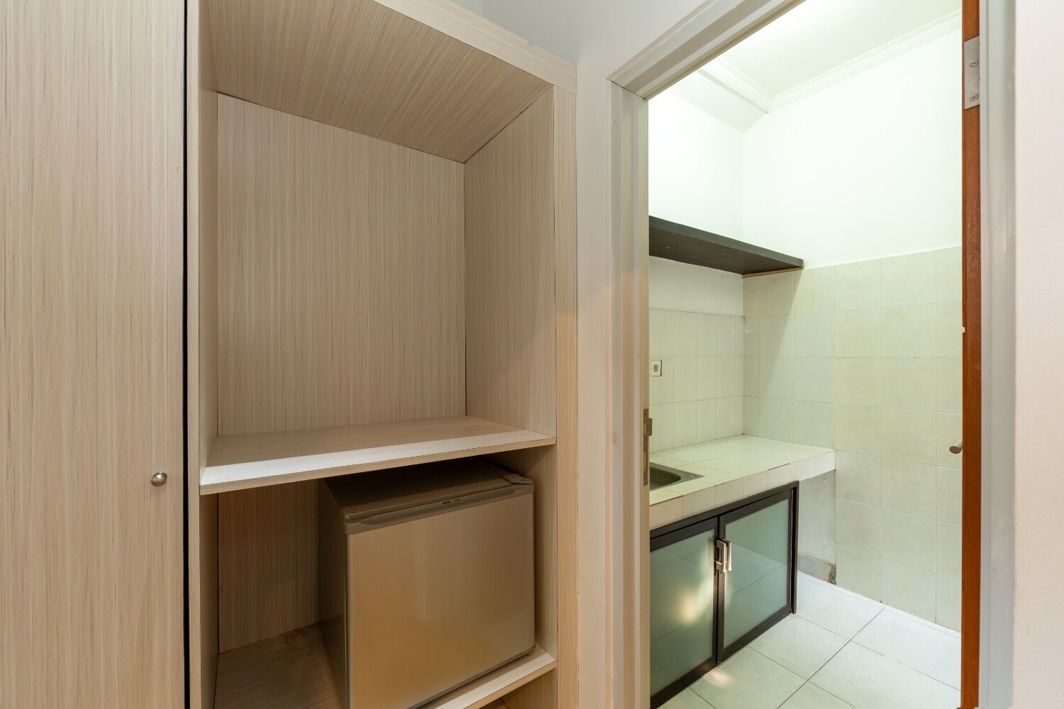 A compact kitchen with a built-in refrigerator, a countertop, and a tiled backsplash.