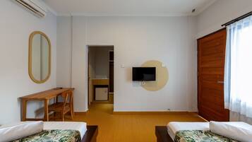 A room with two beds, a desk, a TV mounted on the wall, and a wardrobe.