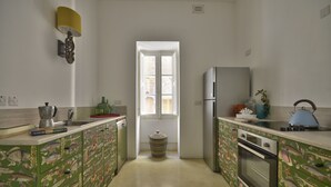 A kitchen with green cabinets, a sink, a stove, and a refrigerator. - Sea Breeze Apartment (Floriana)