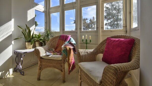 A sunlit room with wicker chairs, a small table, and potted plants. - Sea Breeze Apartment (Floriana)