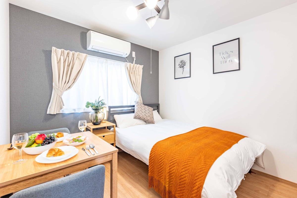 Quarto de hotel com cama, mesa de jantar com café da manhã, janela com cortinas e ar-condicionado fixado na parede.