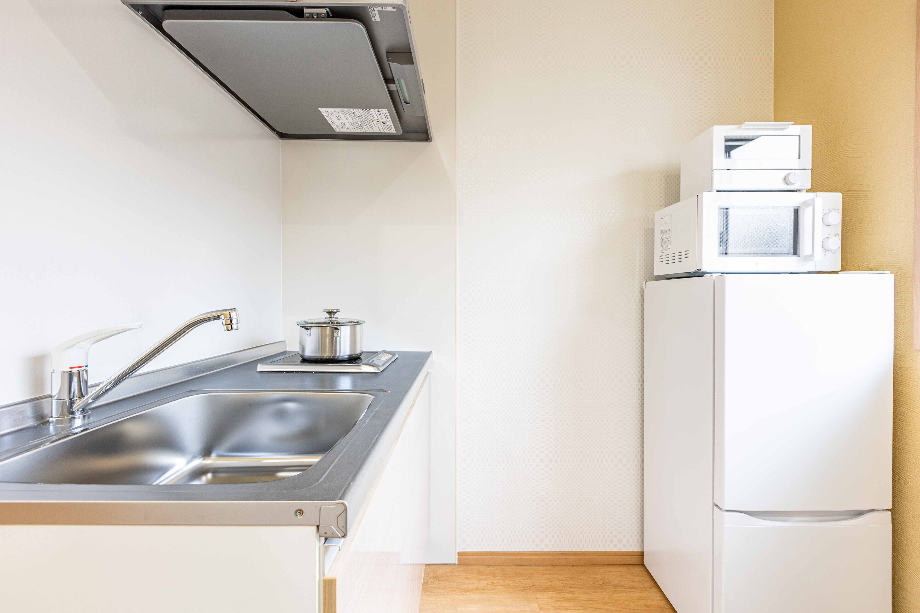A compact kitchen with a stainless steel sink, a microwave, and a refrigerator.