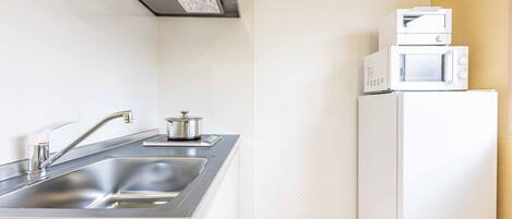 A compact kitchen with a stainless steel sink, a microwave, and a refrigerator.