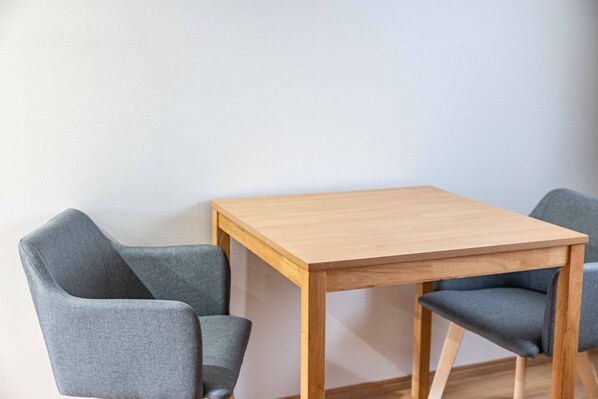 A small wooden table with two grey upholstered chairs.