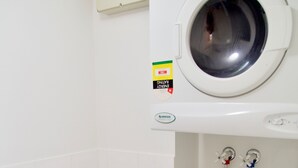 Un área de lavandería compacta con lavadora de carga frontal y secadora de pared.