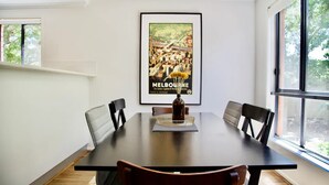 Un comedor con una gran mesa, seis sillas y un cartel enmarcado en la pared.